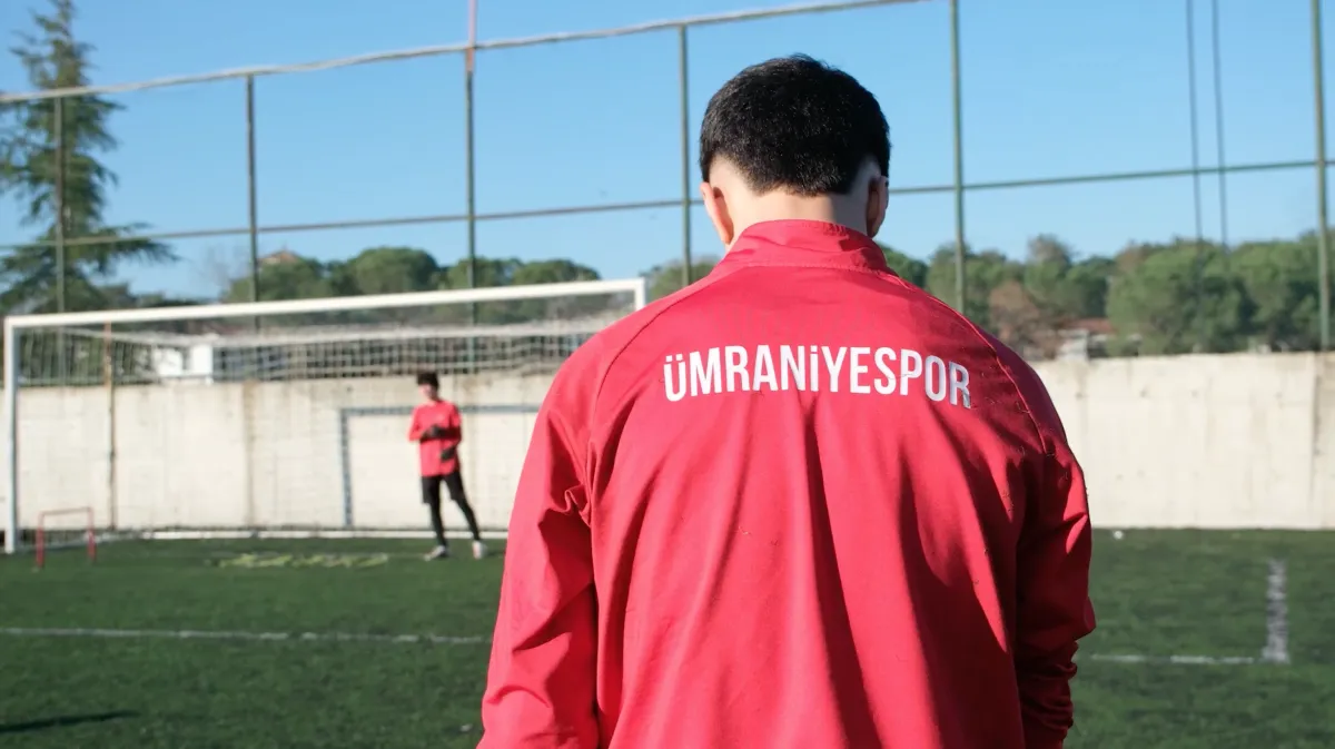 Ein Spieler blickt auf den Platz, auf seiner Jacke steht Ümraniyespor