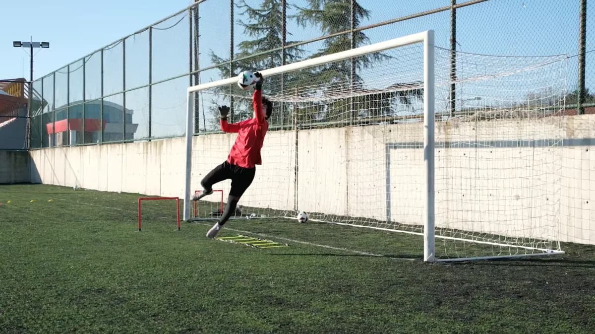 Kaleci üst direğe uzanarak topu kurtarıyor